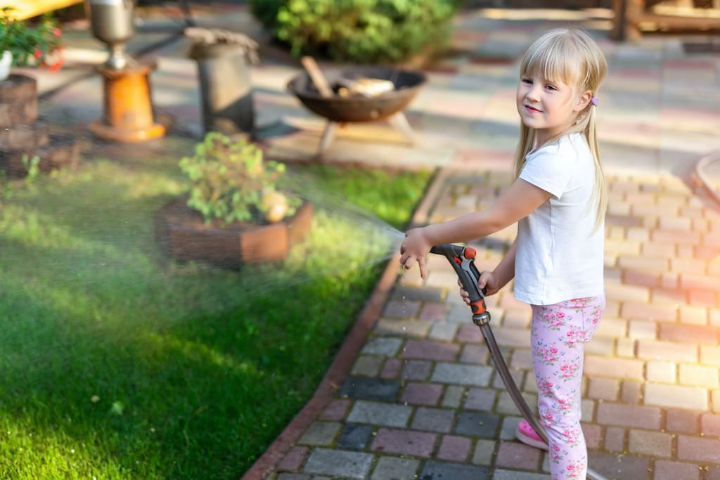 Kleinkind bei Gartenbewässerung